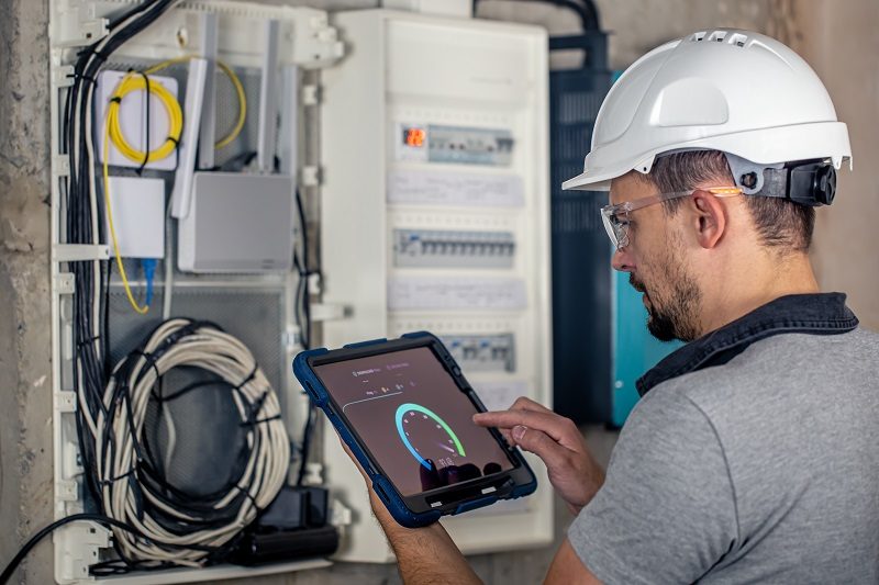 Man, an electrical technician working in a switchboard with fuses. Installation and connection of electrical equipment.